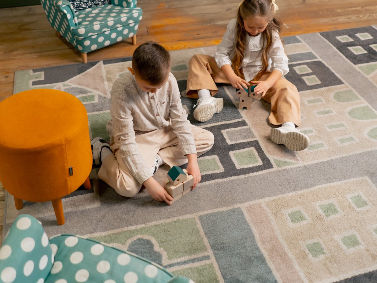 Two children playing on a rug in a bookstore reading corner